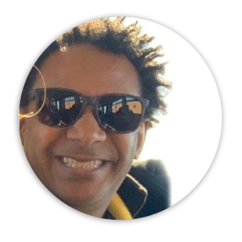 imagem circular. Ernane é um homem negro, usa óculos escuros e sorri. 